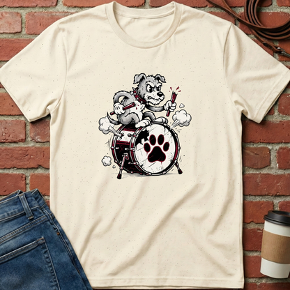 Beige t-shirt with a graphic of a dog playing drums on a brick wall background. Minimalist dog apparel by pemuyo.