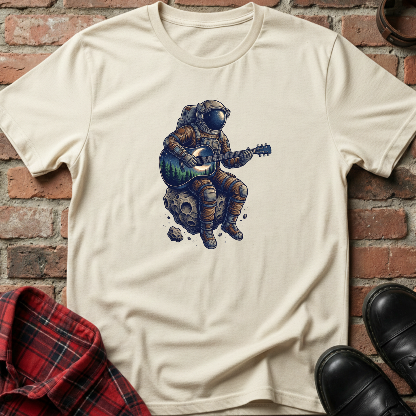 Beige t-shirt with an astronaut playing guitar on a rock graphic against a brick wall. Minimalist music apparel by pemuyo.