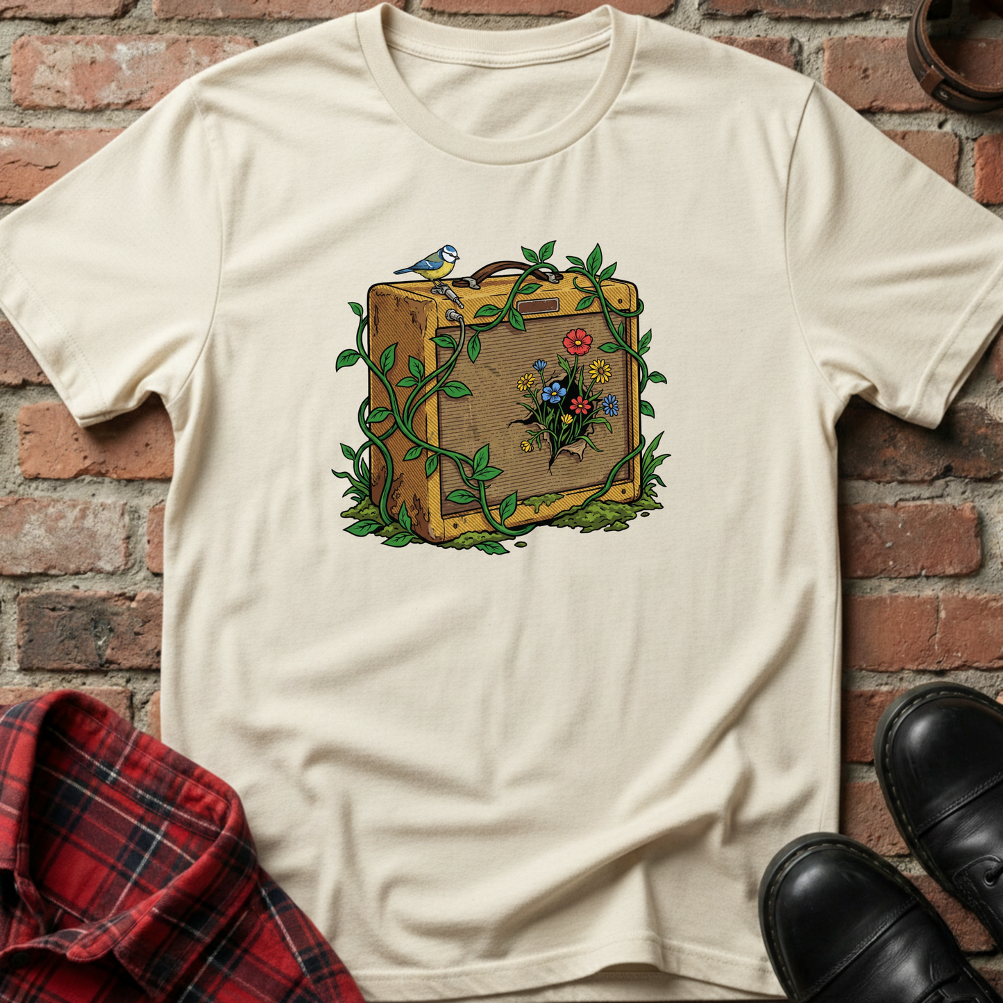 Beige t-shirt with a suitcase and floral design against a brick wall. Minimalist music apparel by pemuyo.