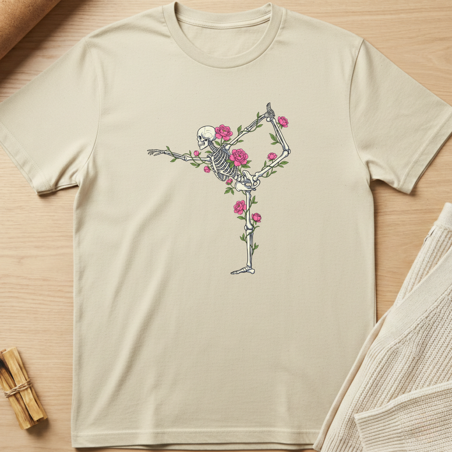 Beige t-shirt with a skeleton and floral design on a wooden surface. Minimalist yoga apparel by pemuyo.