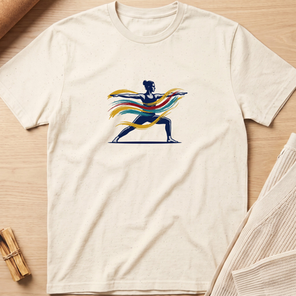 An off-white short-sleeve t-shirt laid flat on a light wood background, featuring a graphic of a dancer in a navy blue silhouette with flowing yellow, orange, and red ribbons. Minimalist yoga apparel by pemuyo.