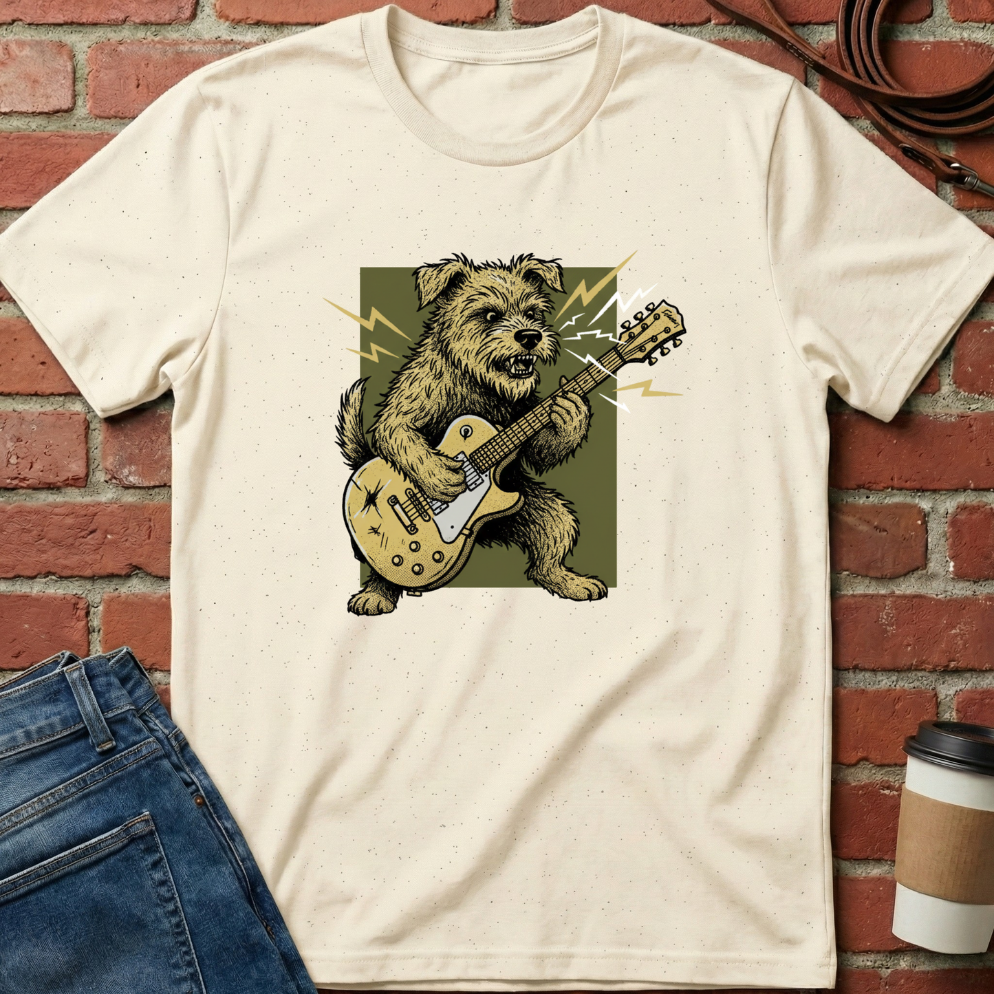 Beige t-shirt with a graphic of a dog playing a guitar on a brick wall background. Minimalist dog apparel by pemuyo.