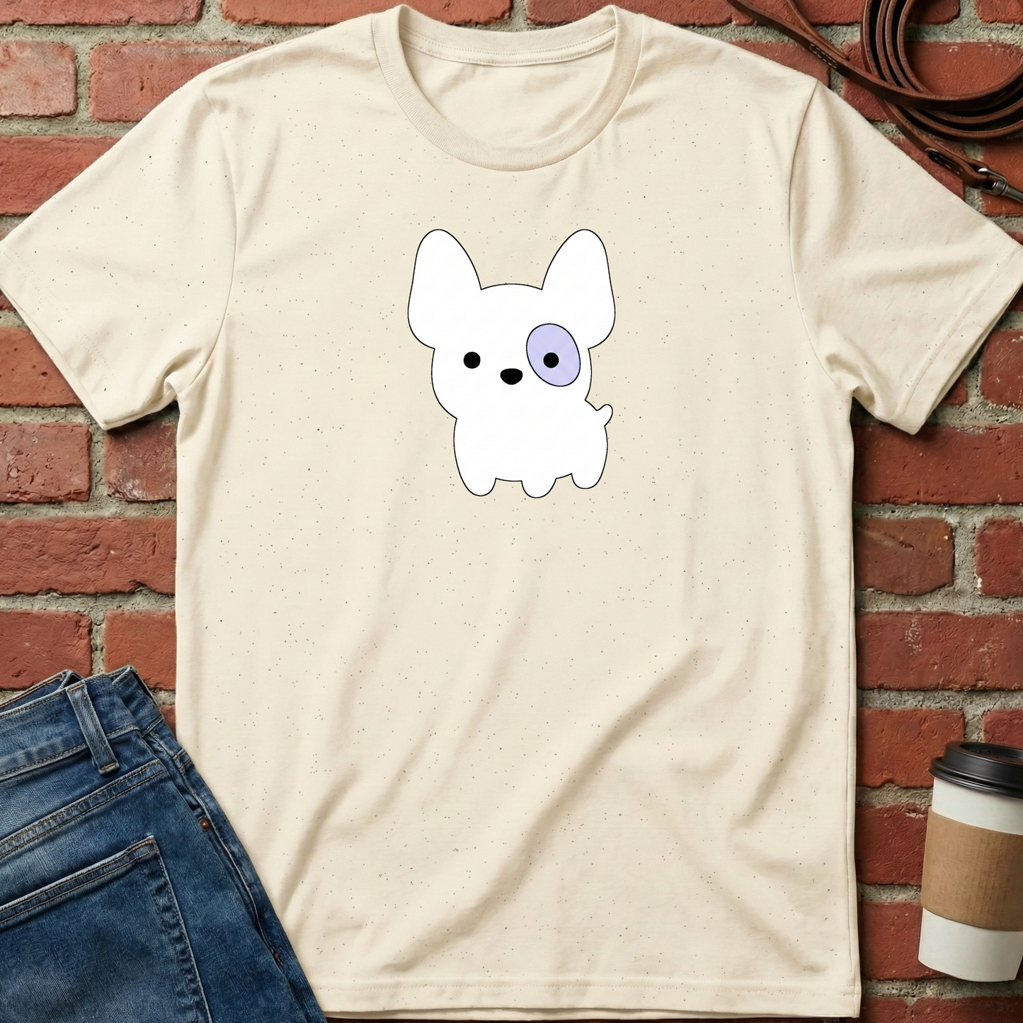 Beige t-shirt with a cartoon dog design on a brick wall background. Minimalist dog apparel by pemuyo.