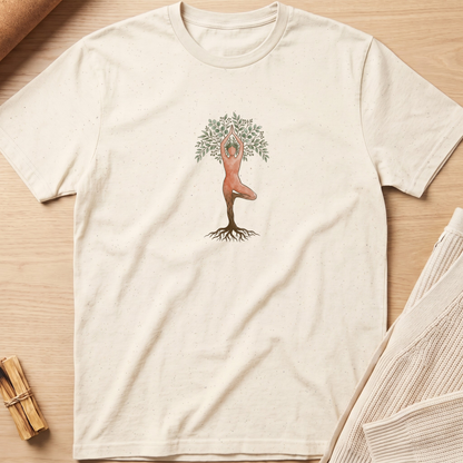 An off-white short-sleeve t-shirt with a central graphic of a tree trunk with roots and a figure in a yoga pose at the top, styled flat on a light wood background. Minimalist yoga apparel by pemuyo.