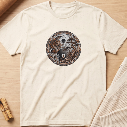 An off-white crewneck t-shirt laid flat on a light wood background, featuring a circular graphic of a yin-yang symbol composed of a black cat and a white cat with a small moon and star in the center. Minimalist yoga apparel by pemuyo.