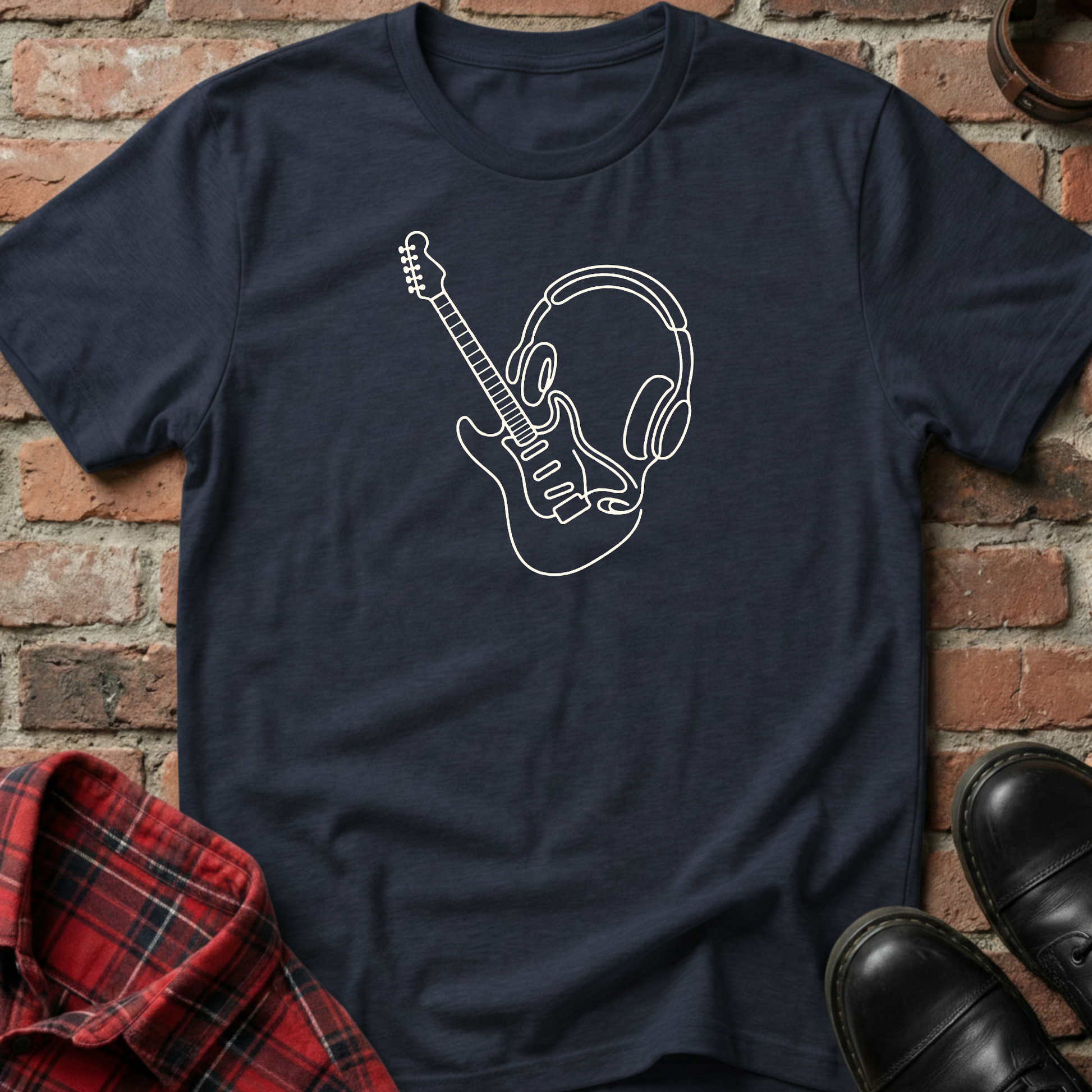 Navy blue t-shirt with white graphic design of a guitar and headphones on a brick background. Minimalist music apparel by pemuyo.
