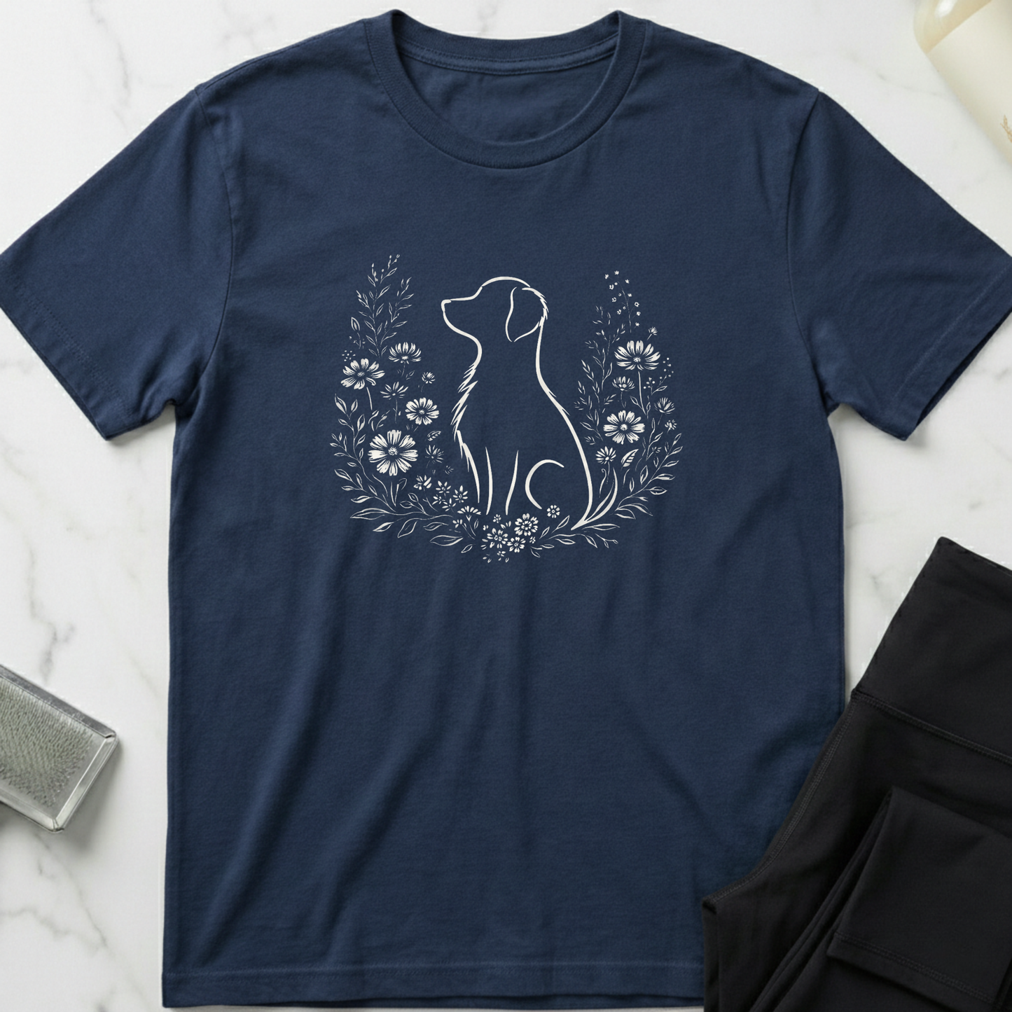 Navy blue t-shirt with a white dog and floral design on a marble surface. Minimalist dog apparel by pemuyo.