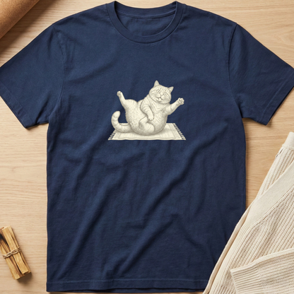 A navy blue short-sleeve t-shirt with a white line art graphic of a stretching cat, laid flat on a light wood background with neutral props. Minimalist yoga apparel by pemuyo.