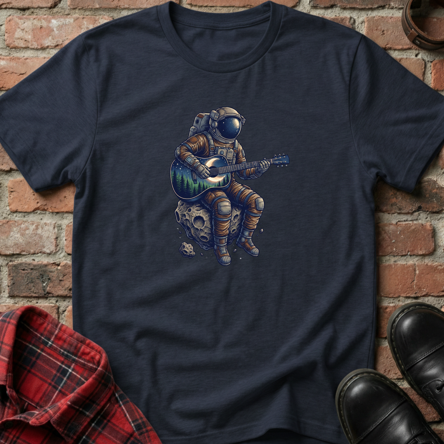 Navy blue t-shirt with an astronaut playing guitar graphic on a brick wall background. Minimalist music apparel by pemuyo.