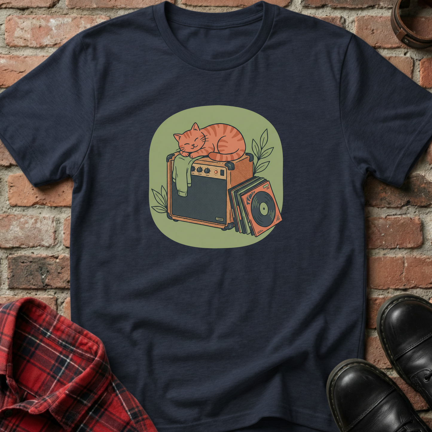 Navy blue t-shirt with a graphic of a cat on an amplifier against a brick wall. Minimalist music apparel by pemuyo.