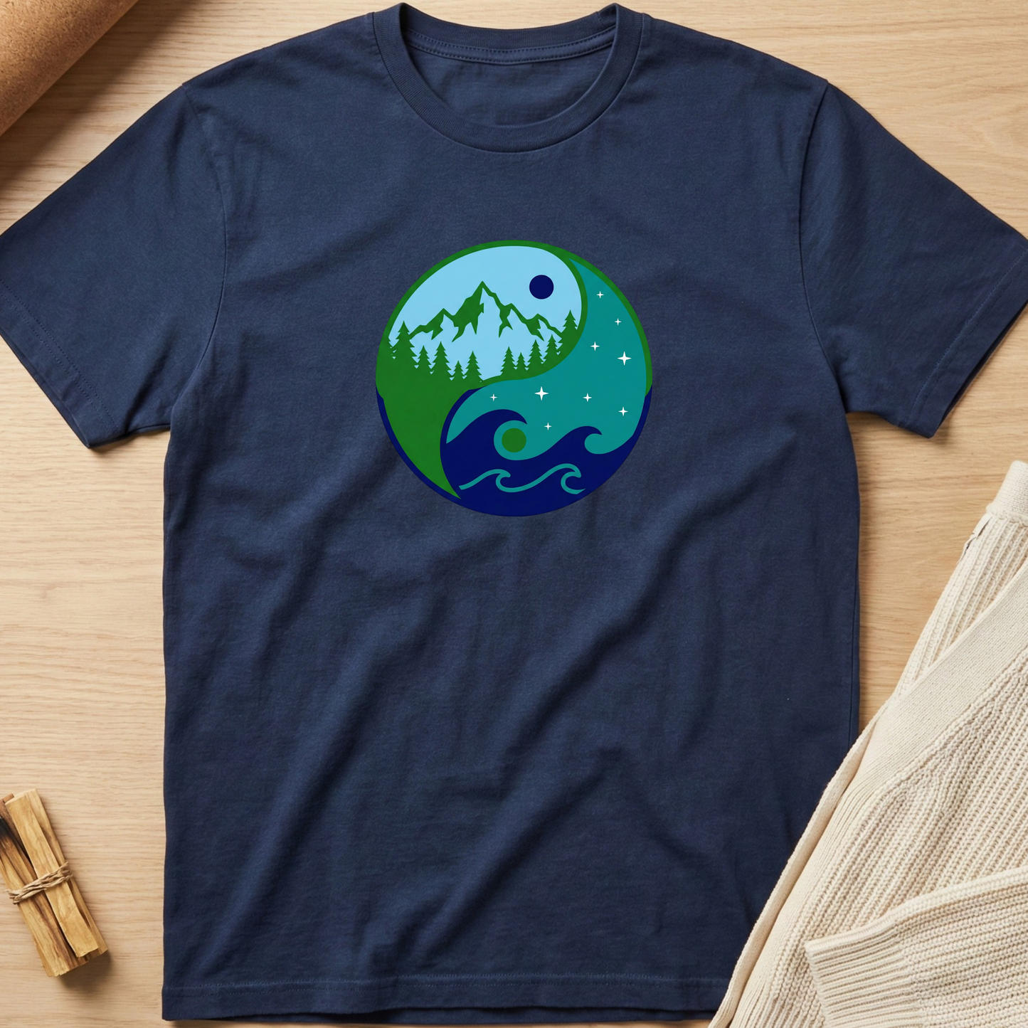 Navy blue t-shirt with a circular design featuring nature elements on a wooden surface. Minimalist yoga apparel by pemuyo.