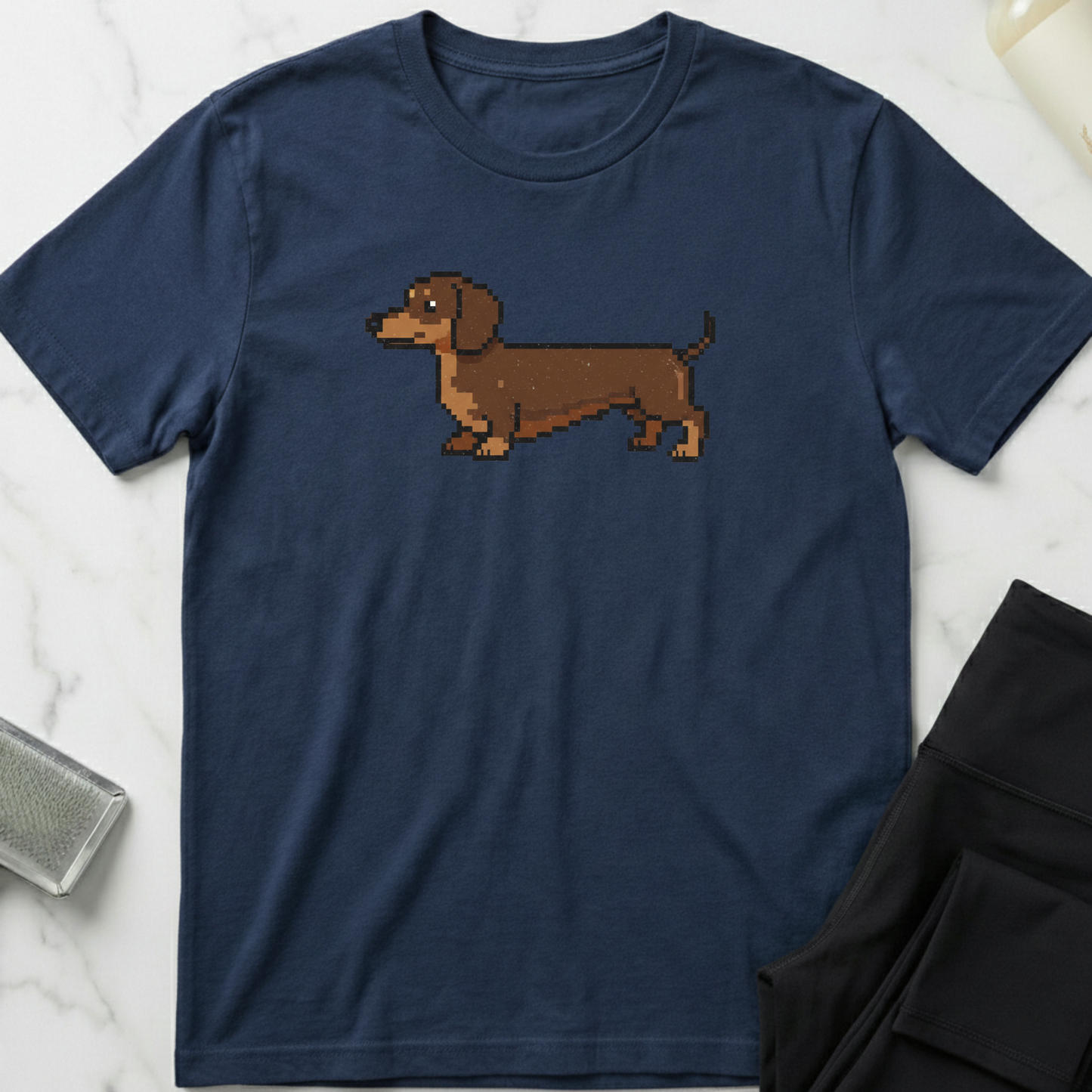 Navy blue t-shirt with a pixelated dachshund graphic on a marble surface. Minimalist dog apparel by pemuyo.