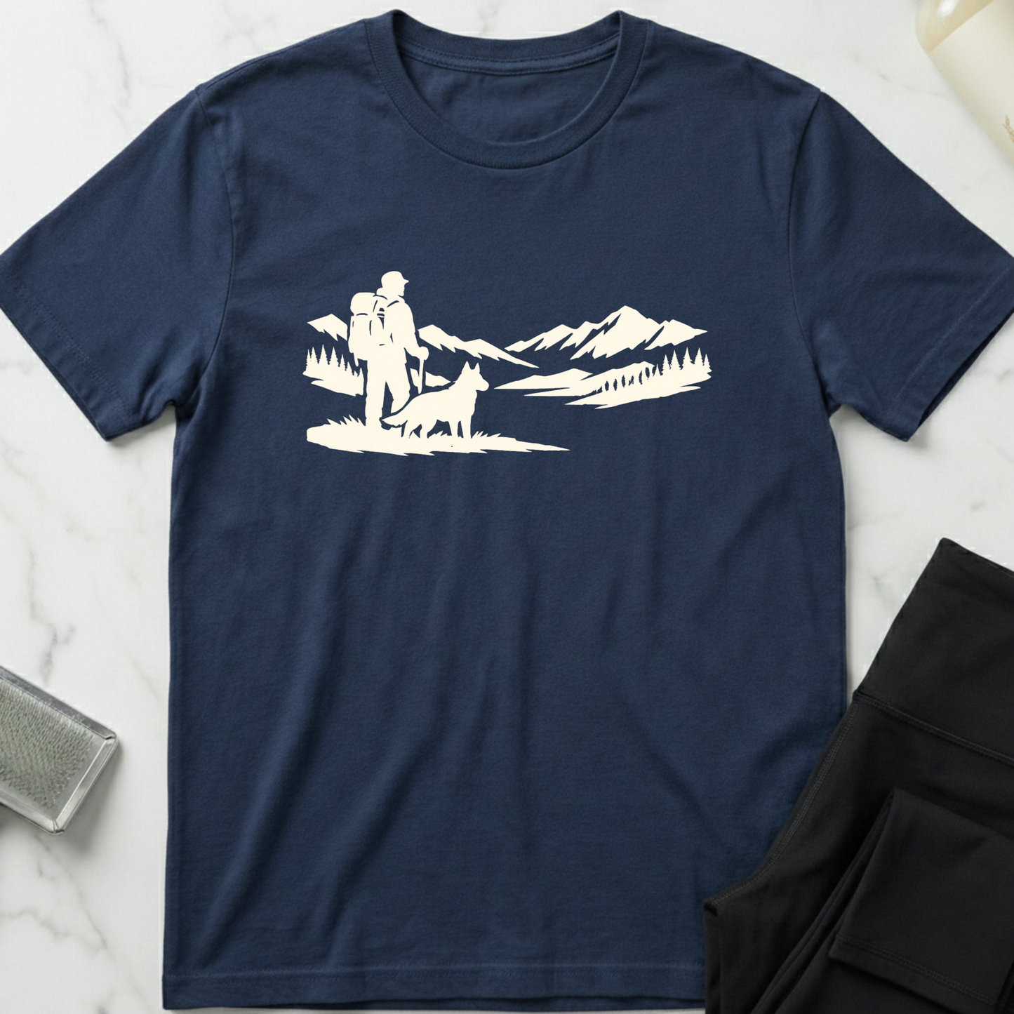 Navy blue t-shirt with white graphic of a person and dog in a mountainous landscape on a marble surface. Minimalist dog apparel by pemuyo.