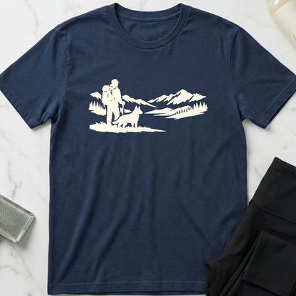 Navy blue t-shirt with white graphic of a person and dog in a mountainous landscape on a marble surface. Minimalist dog apparel by pemuyo.
