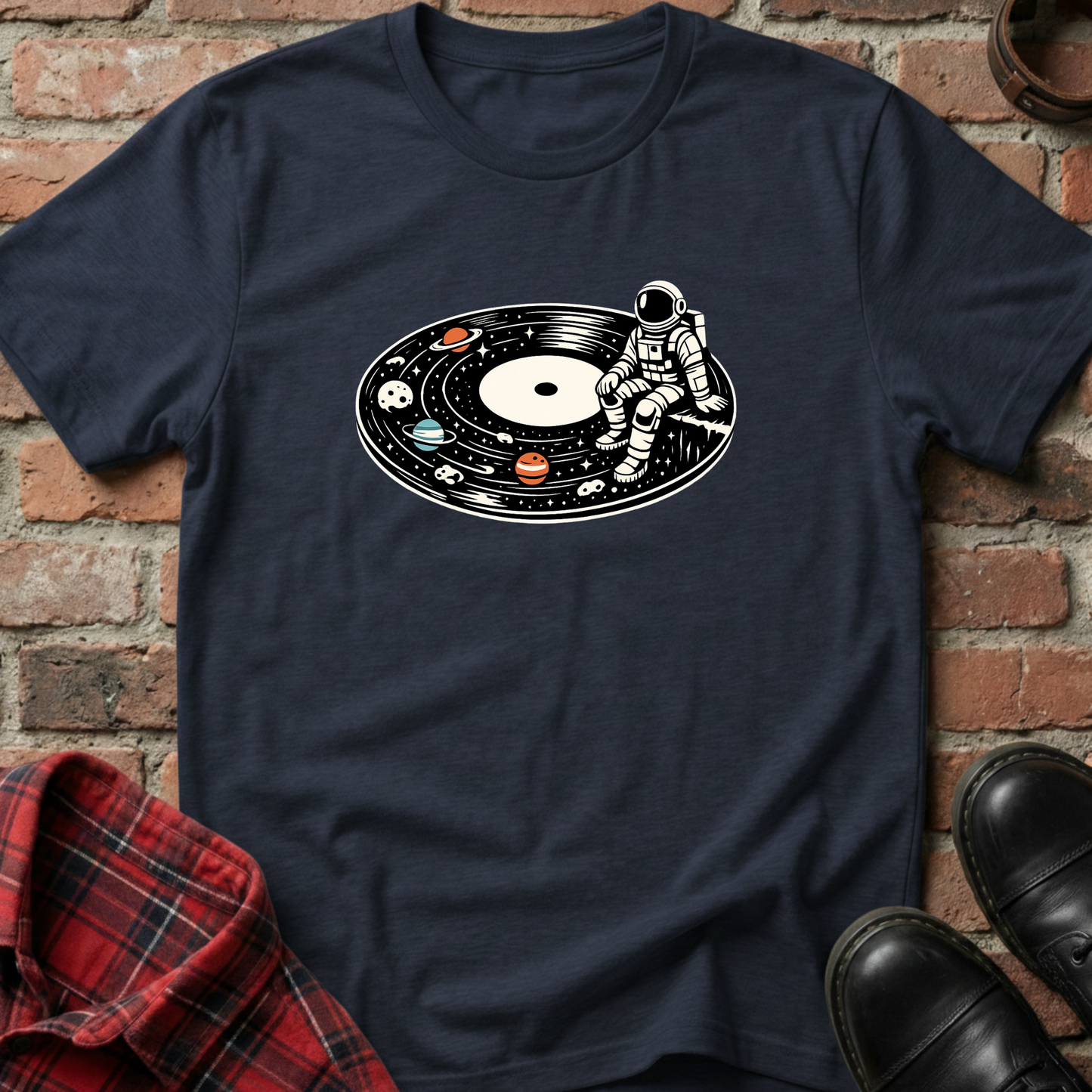 Navy blue t-shirt with an astronaut on a vinyl record design, placed against a brick wall. Minimalist music apparel by pemuyo.