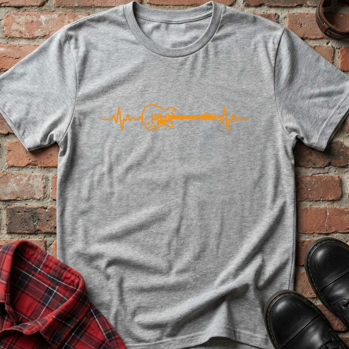Gray t-shirt with orange guitar heartbeat design on a brick surface. Minimalist music apparel by pemuyo.