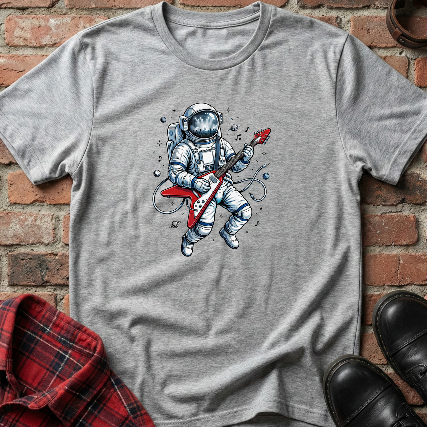 Gray t-shirt with an astronaut playing a guitar graphic on a brick background. Minimalist music apparel by pemuyo.