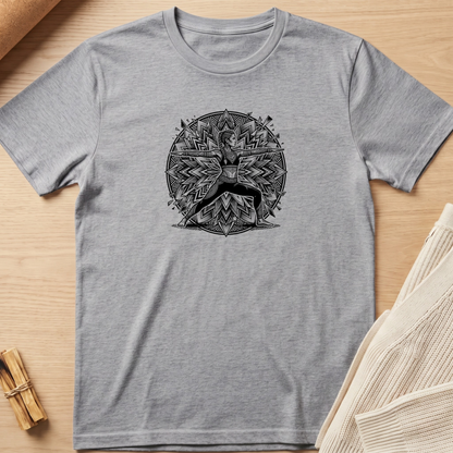 A heather gray crewneck t-shirt featuring a black circular graphic of a deer surrounded by geometric patterns, laid flat on a light wood background with styled props. Minimalist yoga apparel by pemuyo.