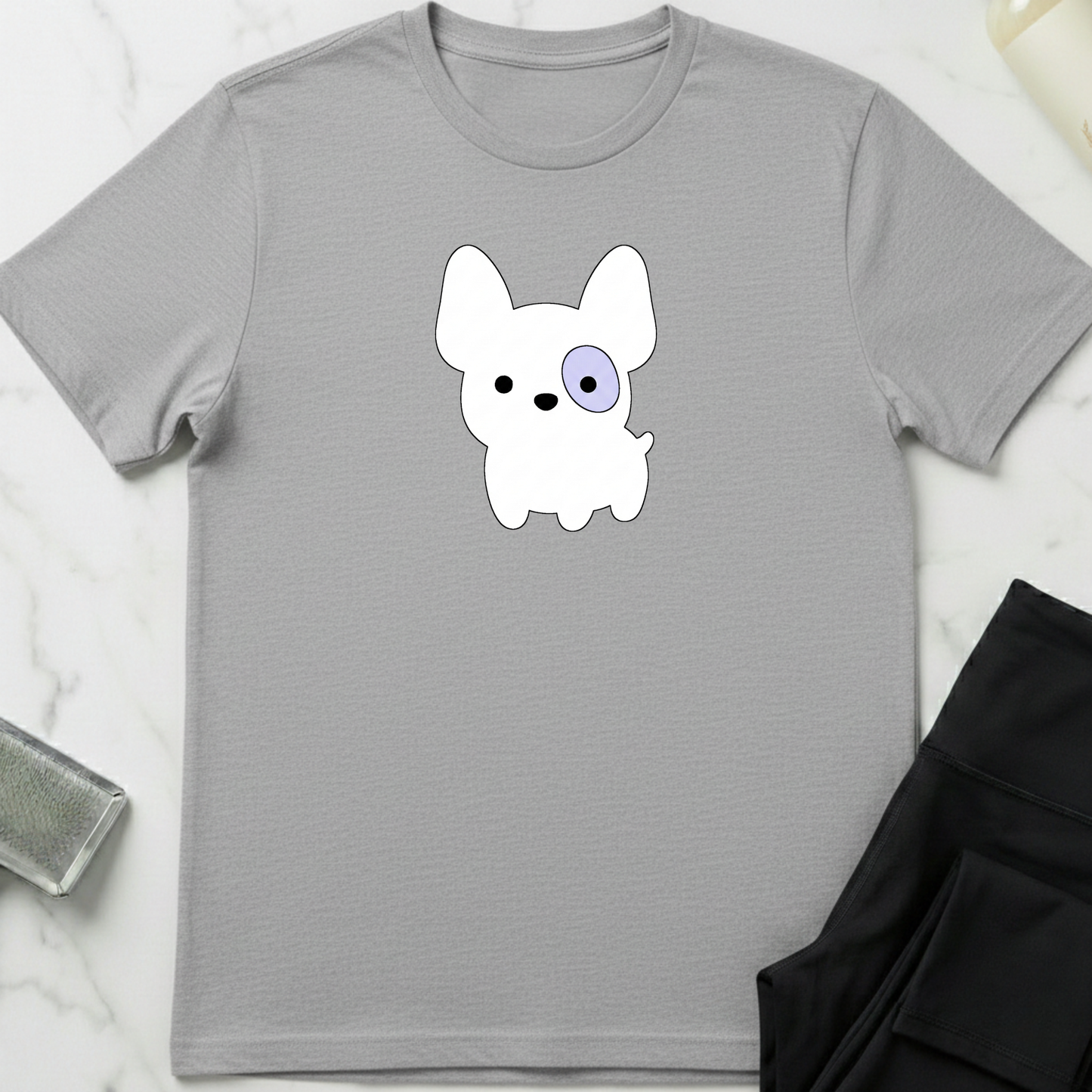 Gray t-shirt with a cartoon dog graphic on a marble surface. Minimalist dog apparel by pemuyo.