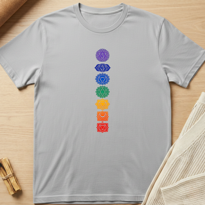 Gray t-shirt with colorful chakra symbols on a wooden surface. Minimalist yoga apparel by pemuyo.