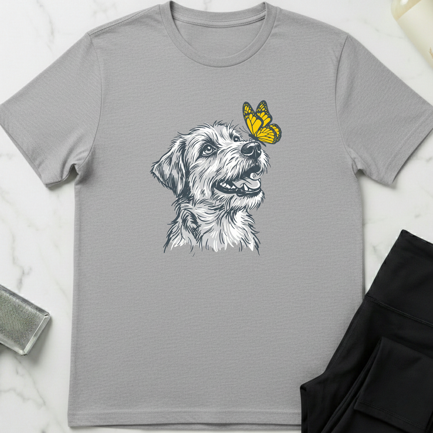 Gray t-shirt with a dog and butterfly graphic on a marble surface. Minimalist dog apparel by pemuyo.