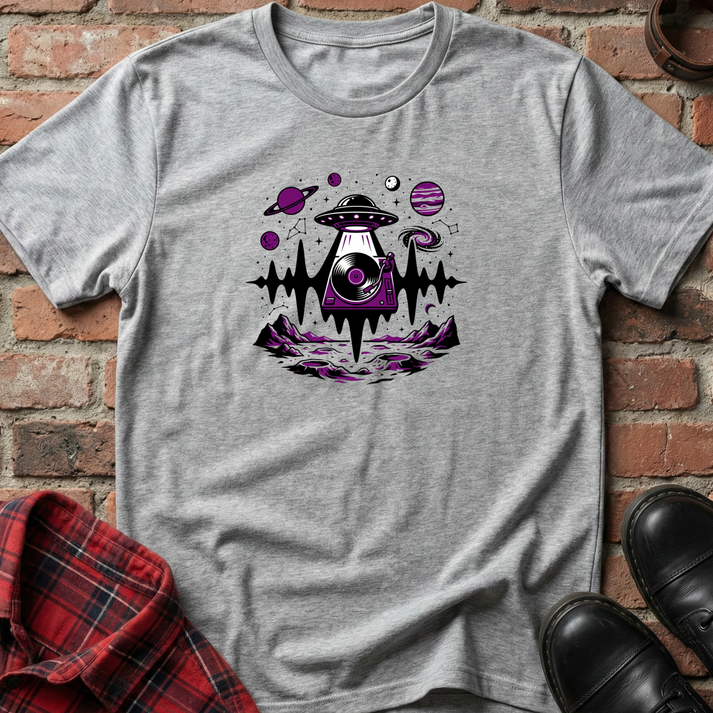 Gray t-shirt with alien spaceship graphic on a brick wall background. Minimalist music apparel by pemuyo.