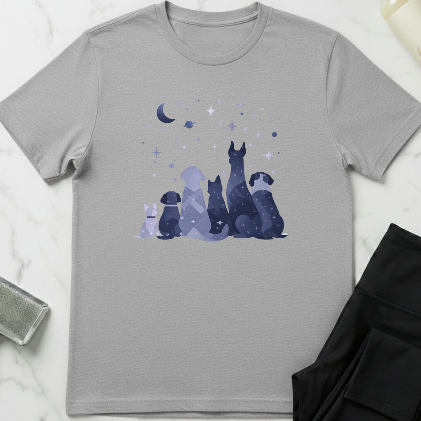 Gray t-shirt with a graphic of dogs under a moon and stars on a white marble surface. Minimalist dog apparel by pemuyo.