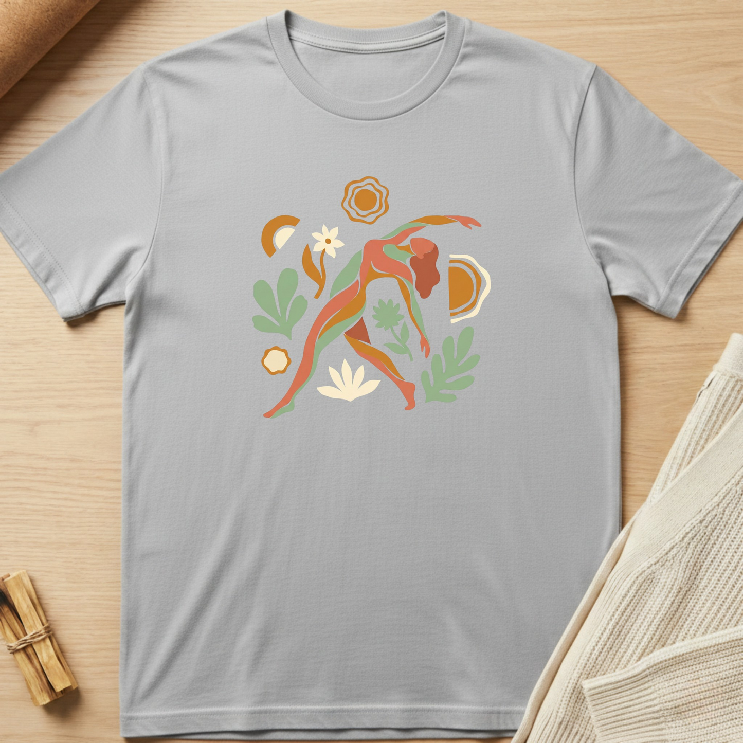 Gray t-shirt with colorful graphic design on a wooden surface. Minimalist yoga apparel by pemuyo.