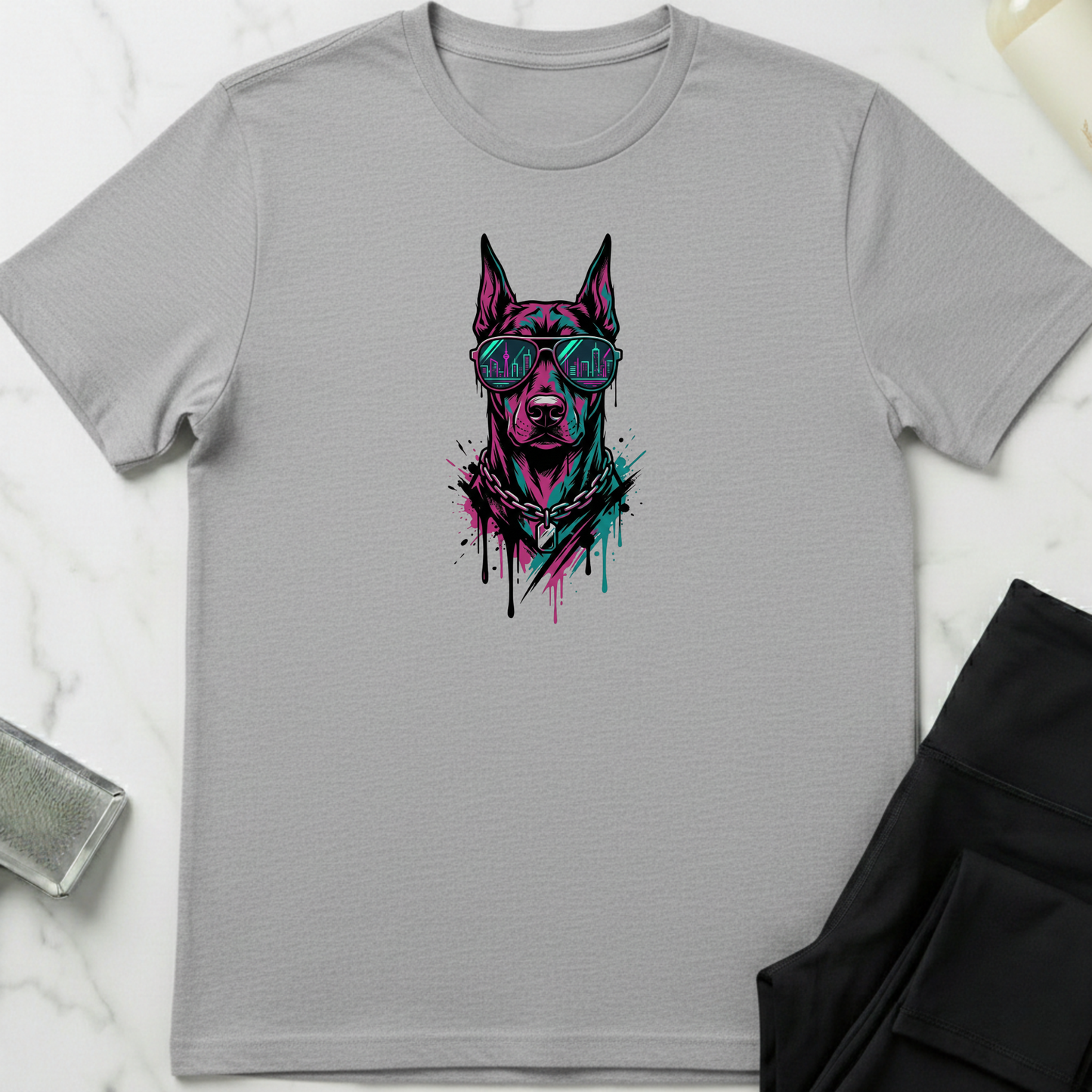 Gray t-shirt with a graphic of a dog wearing sunglasses on a white marble surface. Minimalist dog apparel by pemuyo.