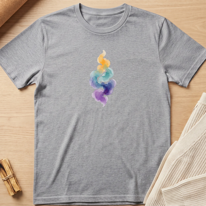 A heather gray short-sleeve t-shirt with a colorful watercolor flame graphic on the chest, laid flat on a light wood background with styled props. Minimalist yoga apparel by pemuyo.