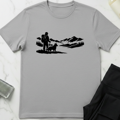 Gray t-shirt with black graphic of a couple and dog in a mountainous landscape on a white marble surface. Minimalist dog apparel by pemuyo.