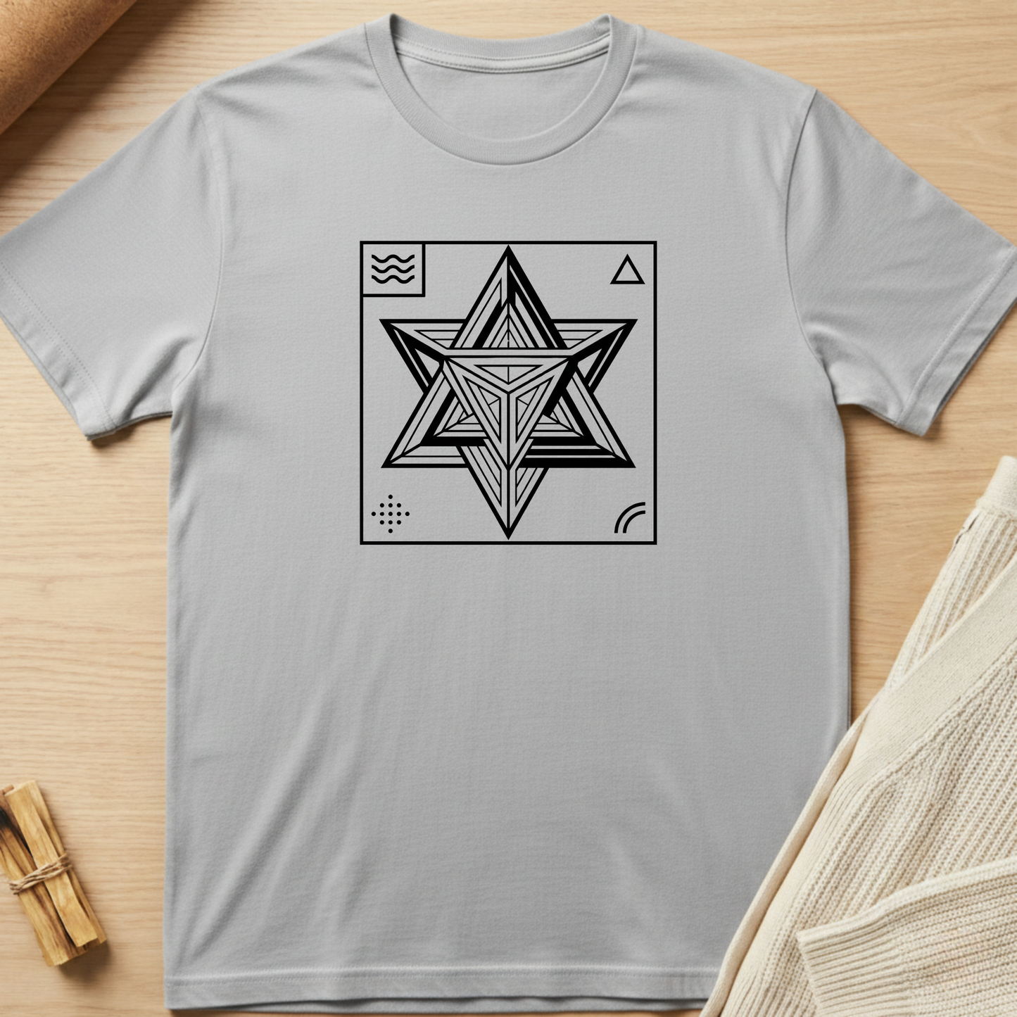 Gray t-shirt with a black geometric star design on a wooden surface. Minimalist yoga apparel by pemuyo.