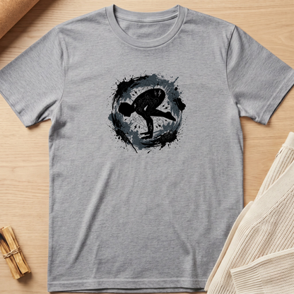 A heather gray short-sleeve t-shirt with a black and dark gray circular graphic print on the chest, laid flat on a light wood background with styled props. Minimalist yoga apparel by pemuyo.
