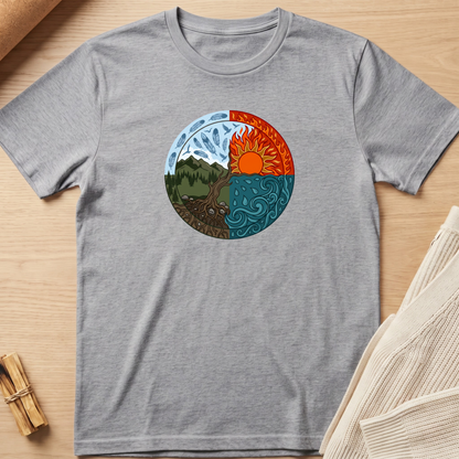 A heather gray short-sleeve t-shirt laid flat on a light wood surface, featuring a circular graphic of a yin-yang style nature design with a mountain and tree on one side and a sun over water on the other. Minimalist yoga apparel by pemuyo.