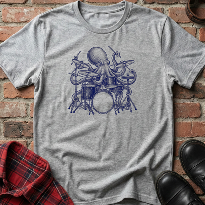 Gray t-shirt with blue octopus playing drums design on a brick surface. Minimalist music apparel by pemuyo.