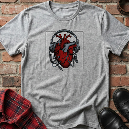 Gray t-shirt with a red heart and headphones graphic on a brick surface. Minimalist music apparel by pemuyo.