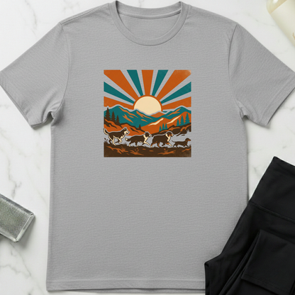 Gray t-shirt with a graphic design of mountains and sun on a white surface. Minimalist dog apparel by pemuyo.