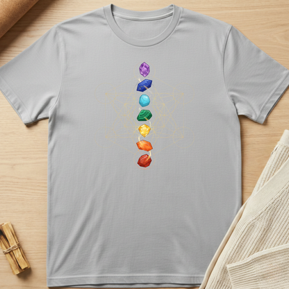 Gray t-shirt with colorful chakra stones design on a wooden surface. Minimalist yoga apparel by pemuyo.
