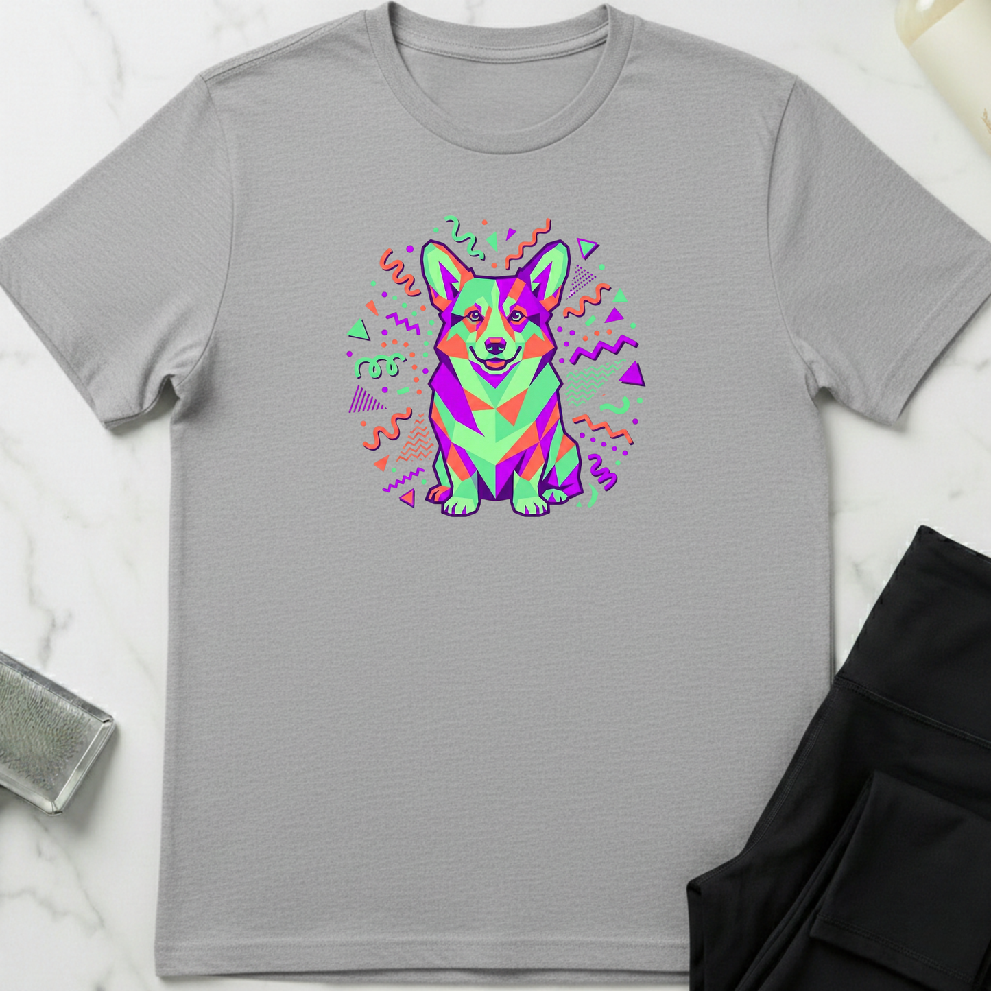 Gray t-shirt with a colorful dog graphic on a white marble surface. Minimalist dog apparel by pemuyo.