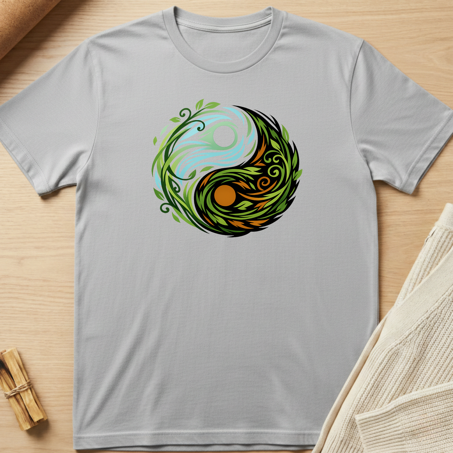 Gray t-shirt with a colorful yin yang symbol design on a wooden surface. Minimalist yoga apparel by pemuyo.