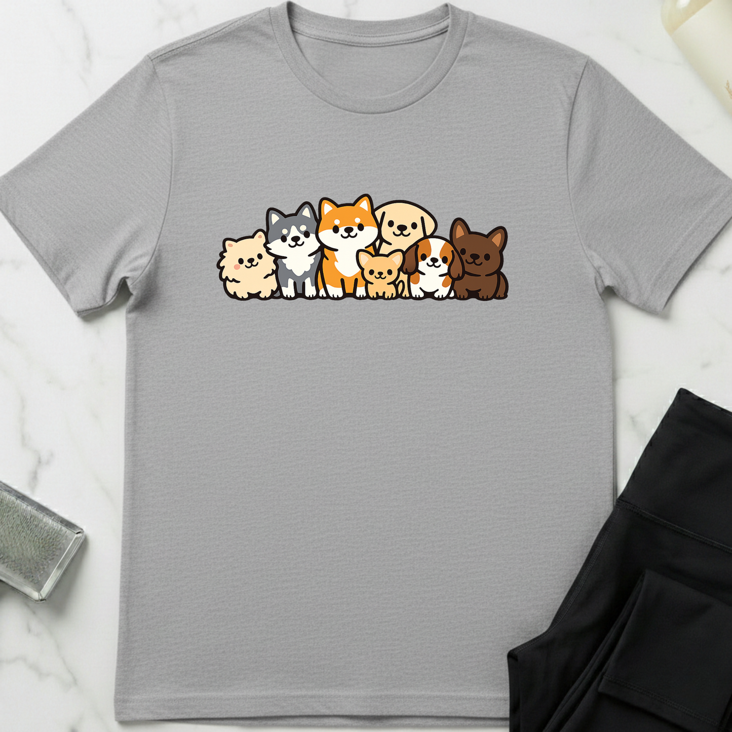 Gray t-shirt with cartoon dog illustrations on a white marble surface. Minimalist dog apparel by pemuyo.