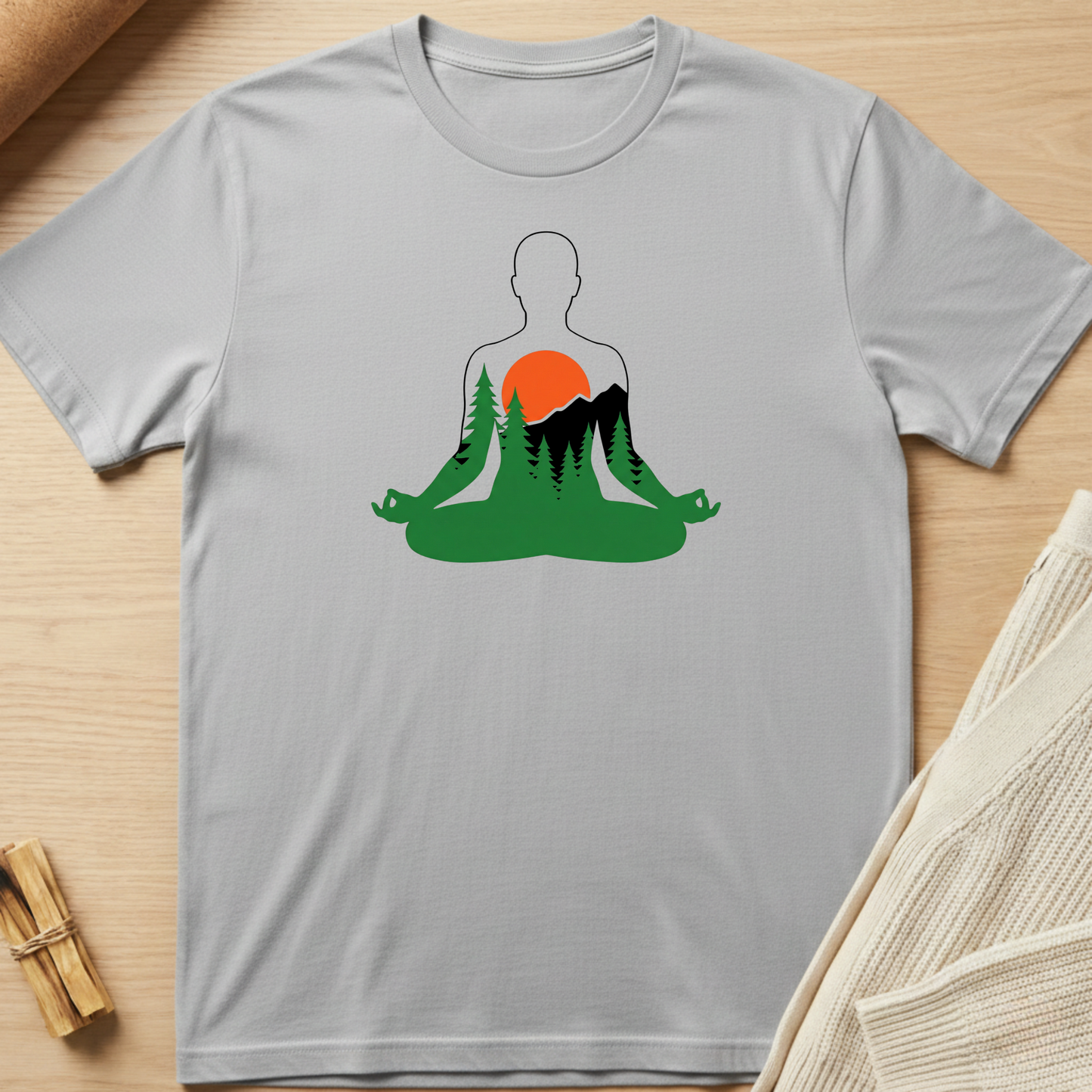 Gray t-shirt with a graphic design of a person meditating in nature on a wooden surface. Minimalist yoga apparel by pemuyo.