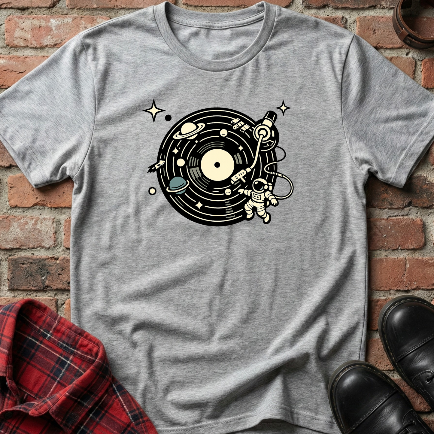 Gray t-shirt with space-themed design on a brick surface. Minimalist music apparel by pemuyo.