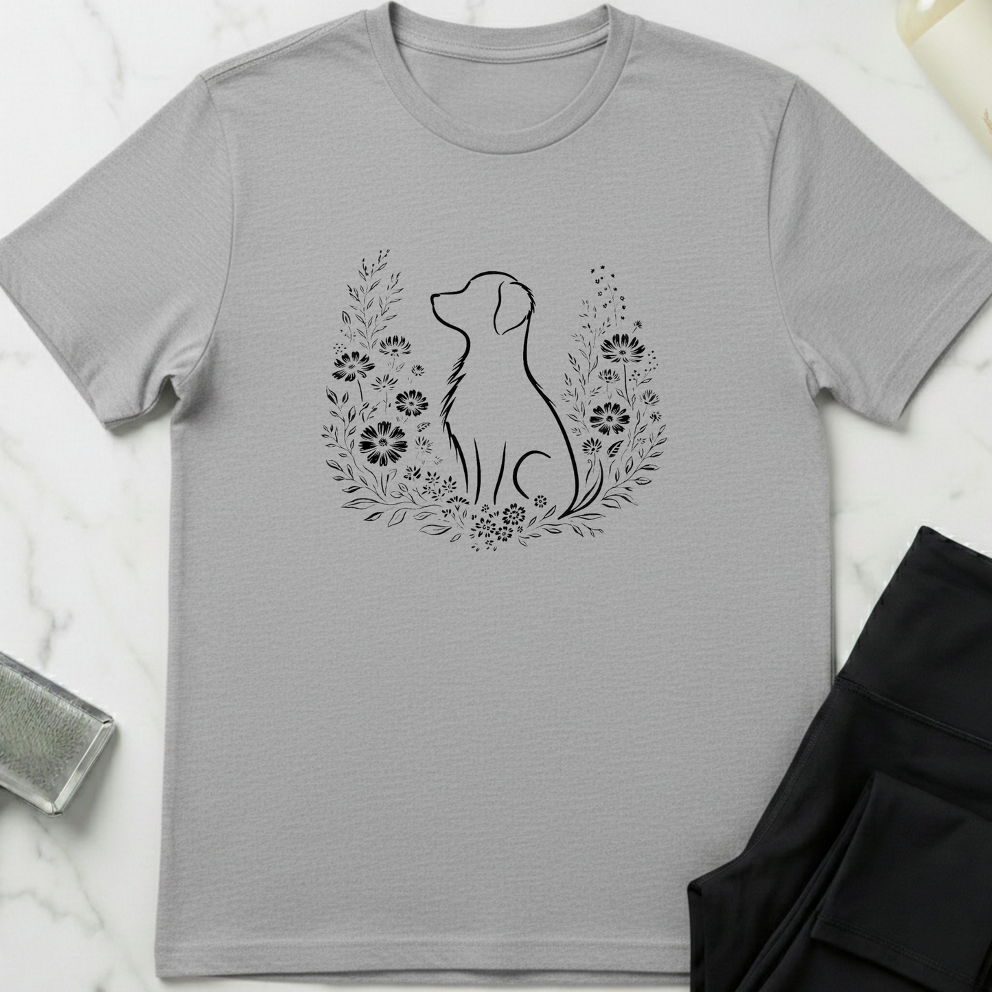Gray t-shirt with a dog silhouette and floral wreath design on a marble surface. Minimalist dog apparel by pemuyo.