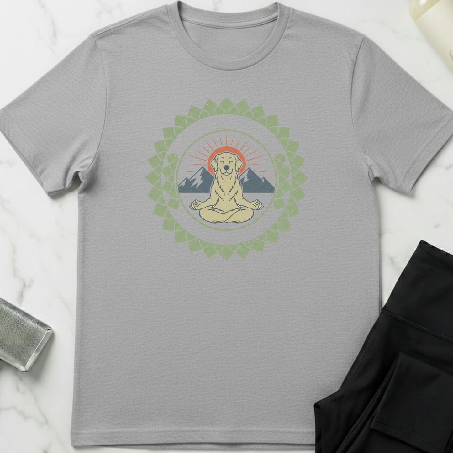 Gray t-shirt with a graphic of a meditating dog surrounded by mountains and a mandala on a white marble surface. Minimalist yoga apparel by pemuyo.
