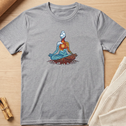 A heather gray short-sleeve t-shirt featuring a colorful graphic of a meditating figure with blue and orange tones, laid flat on a light wood background with styled props. Minimalist yoga apparel by pemuyo.