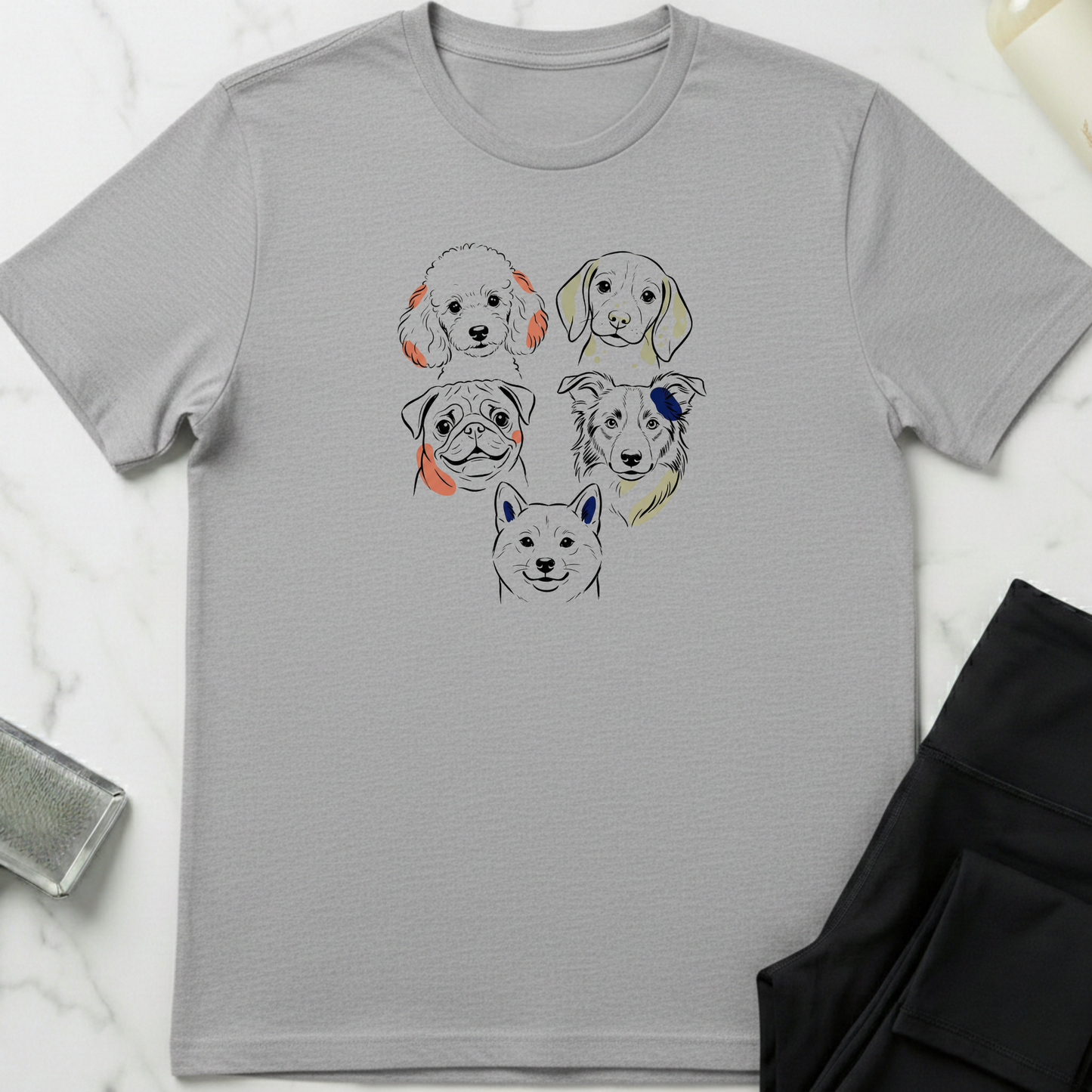 Gray t-shirt with dog illustrations on a white marble surface. Minimalist dog apparel by pemuyo.