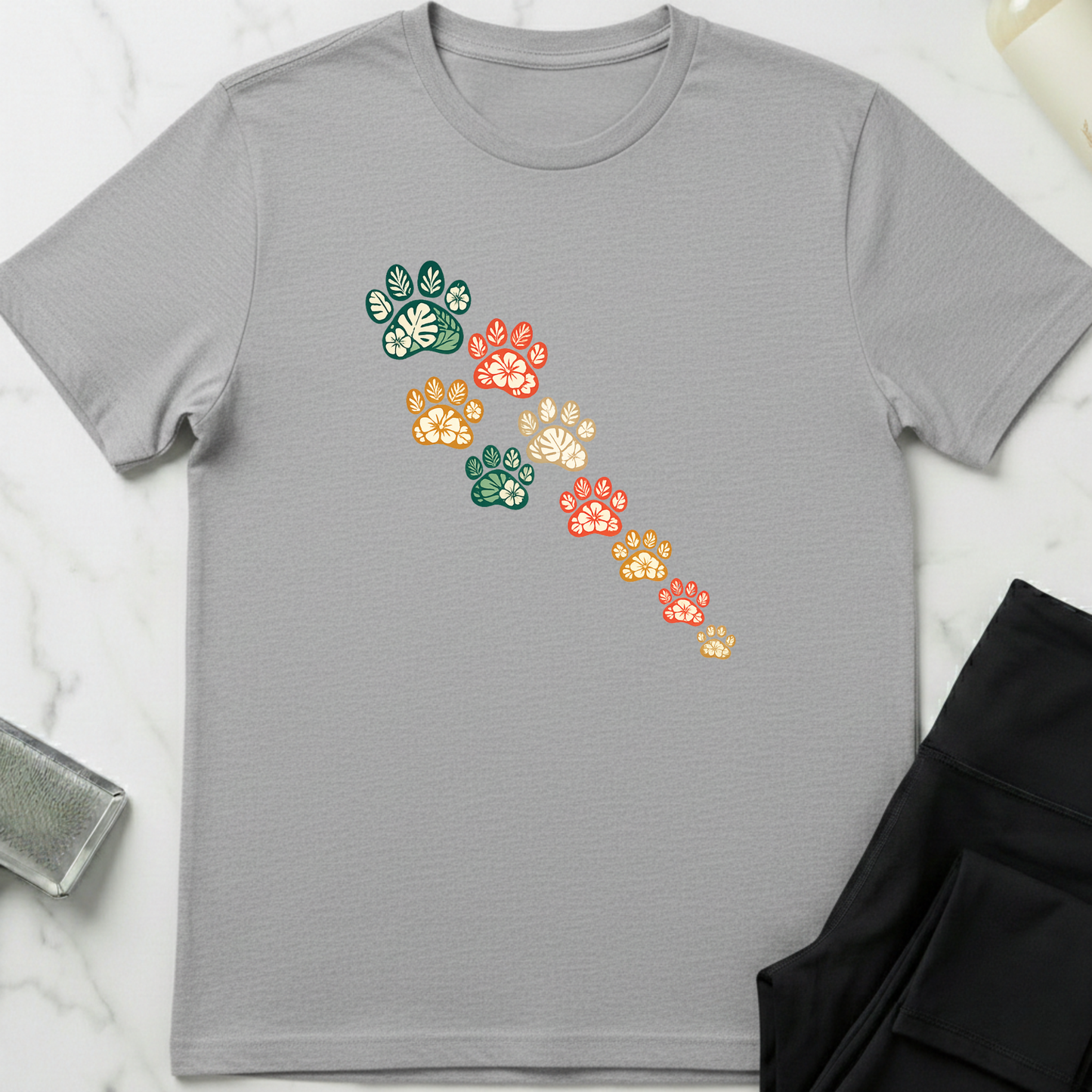 Gray t-shirt with colorful paw print design on a light gray background. Minimalist dog apparel by pemuyo.