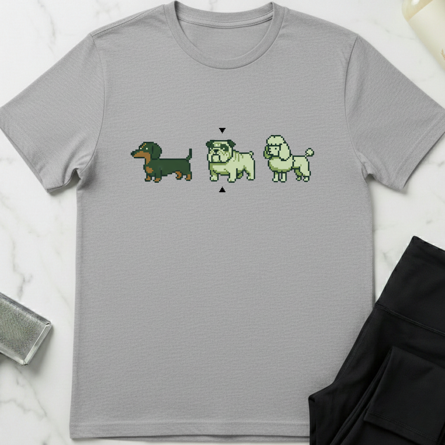 Gray t-shirt with pixelated dog illustrations on a white marble surface. Minimalist dog apparel by pemuyo.