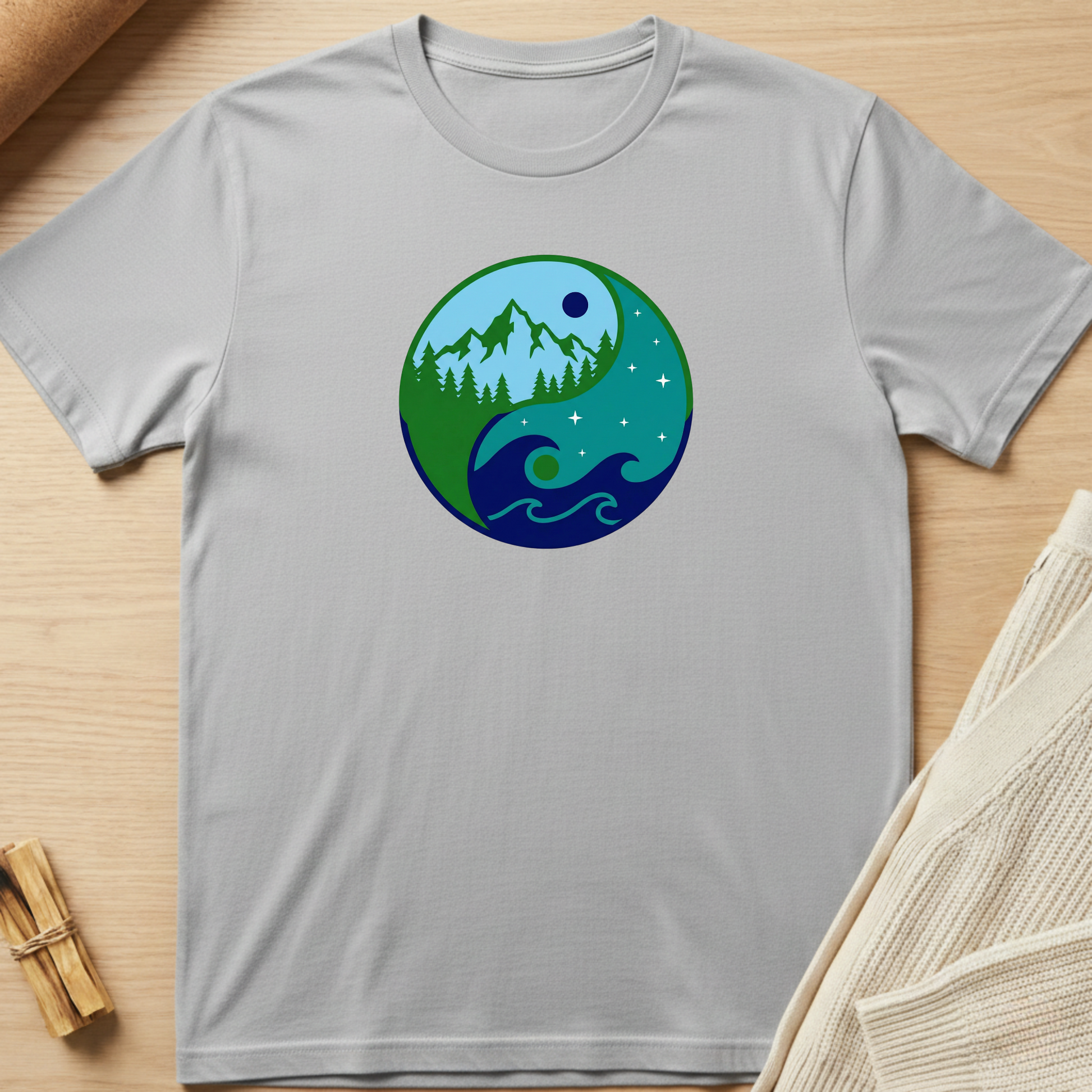 Gray t-shirt with a circular design featuring nature elements on a wooden surface. Minimalist yoga apparel by pemuyo.